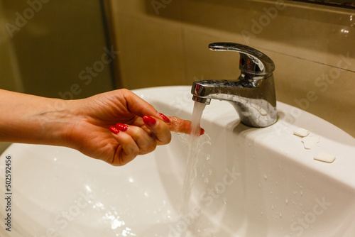 Hand washing underwater from a faucet. leanliness, water saving, washing dishes in a bright Scandinavian interior photo