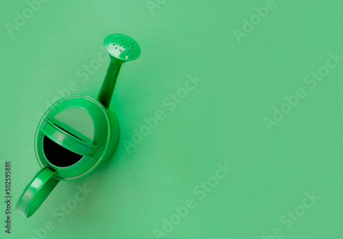 green watering can on green background. Creative concept of investment, growth, success in business and life or hello summer. Top view Flat lay