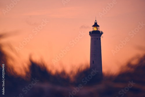 Lighthouse in warm morning glow above the dunes. High quality photo