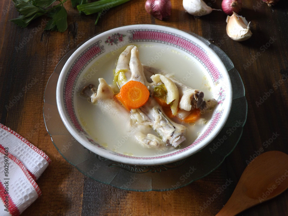 Chicken feet soup, hot and spicy served in white bowl on wooden table. Known as sop ceker in Indonesia. Commonly mixed with vegetable such as carrot. Delicious, tasty, refreshing. Focus selection. Chicken feet soup, hot and spicy served in white bowl on wooden table. Known as sop ceker in Indonesia. Commonly mixed with vegetable such as carrot. Delicious, tasty, refreshing. Focus selection.