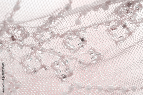 Lace skirt decoration, beadwork, close-up, selective focus. Beads thread clothing detail macro, pastel color