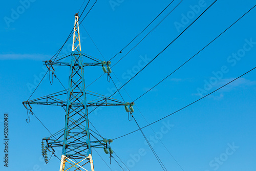 Background, view or scene of steel tower of electric main or electricity transmission line with the wires silhouette on background of clear blue sky