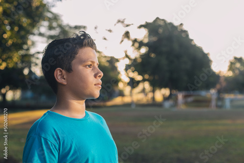 Hispanic boy looking at the horizon in the forest, with a thinking expression