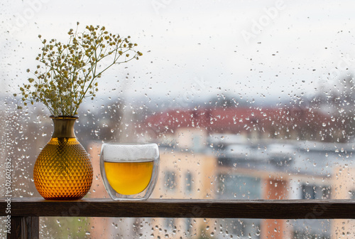 Canvastavla hot tea in thermo glass on background window with raindrops