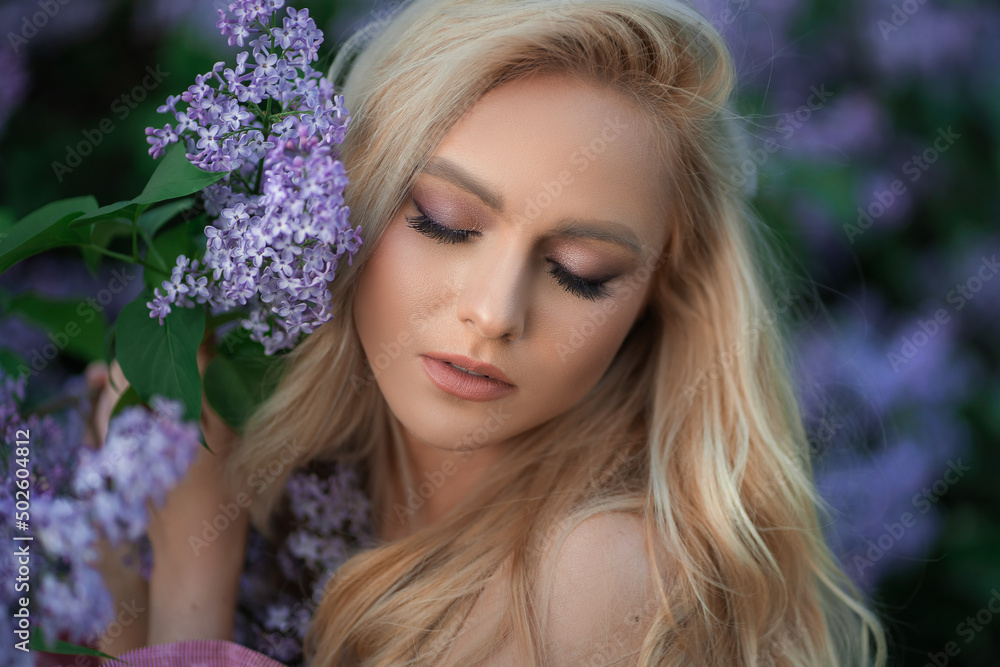 Fototapeta premium very beautiful girl in a pink top in purple flowers with closed eyes