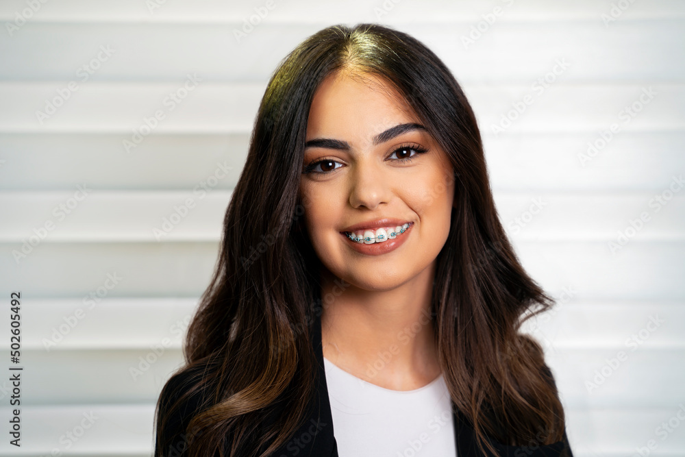 Studio shot of beautiful 20 year old woman with pretty smile and dental braces 