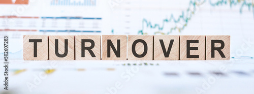 On a light background, graphs, diagrams and wooden cubes with the word TURNOVER.