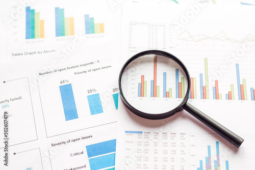 Business charts with magnifying glass, workplace businessman
