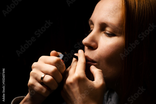 Woman smokes marijuana, cannabis through a device on a black background.