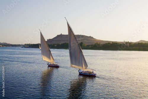 Egypt, Aswan, Two feluccas sail up Nile River at sunset photo