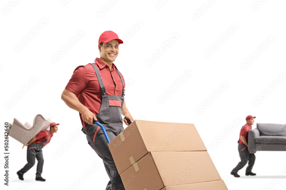 Mover pushing a hand-truck and other workers carrying furniture Mover pushing a hand-truck and other workers carrying furniture