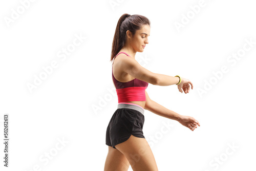 Fototapeta Naklejka Na Ścianę i Meble -  Profile shot of a fit young woman walking checking her sports arm-band
