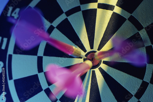 Close-up of three darts in the bull's-eye of a dartboard