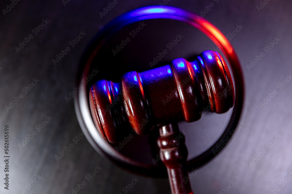 Law theme. Court of law trial in session. Judge gavel on wooden table with police emergency services light. Mallet of judge on dark background. Justice human rights concept. Copy space Law theme. Court of law trial in session. Judge gavel on wooden table with police emergency services light. Mallet of judge on dark background. Justice human rights concept. Copy space