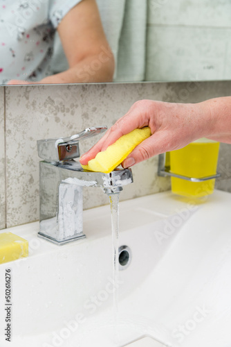 woman cleans a faucet in the bathroom.