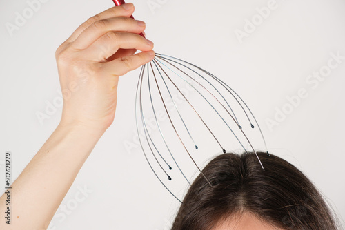 Εκτύπωση καμβά A woman with a metal flexible massager for self-massage of the head on a white b