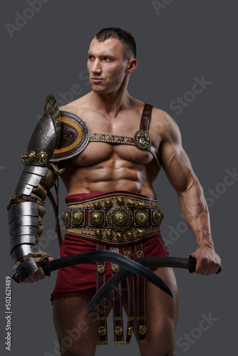 Studio shot of handsome ancient gladiator with naked torso dressed in light armor.