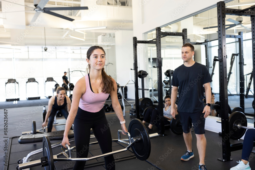 Young woman in brightly lit gym look straight ahead and doing deadlifts with trap bar. deadlift Young woman in brightly lit gym look straight ahead and doing deadlifts with trap bar. deadlift