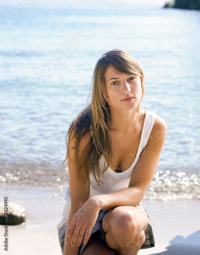 Young woman crouching down by the edge of a lake