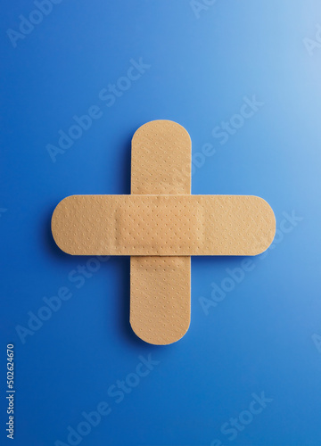 Sticking plasters forming a cross on a blue background photo