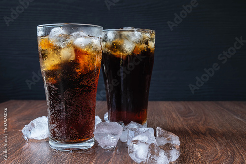 Cola in glass and . ice cubes on wooden background
