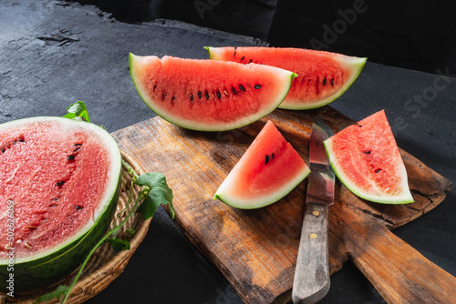 Watermelon slices cut in half on a wooden cutting board.