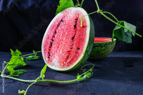 Fresh Water melon fruit cut in half on a black background.