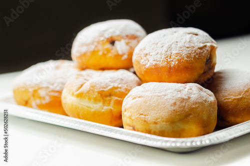 Berliner Pfannkuchen, a German donut, traditional yeast dough deep fried filled with chocolate cream and sprinkled with powdered sugar photo