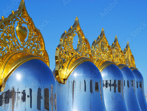 Monument to Nesting dolls with golden kokoshniks on a blue sky photo