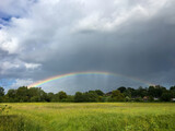 A perfect rainbow forms an arc across the stormy sky