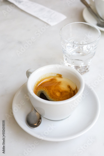 A cup of espresso and a glass of water after coffee.