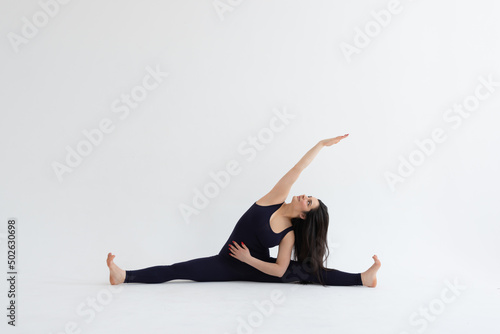 Young beautiful woman practicing yoga on a white background. Young beautiful girl doing exercises at home. Harmony, balance, meditation, relaxation, healthy lifestyle concept 