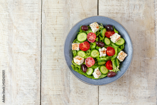 Green vegan salad from vegetables and green leaves mix, cheese, tomatoes and cucumber. Concept for a tasty and healthy meal. Top view. Copy space