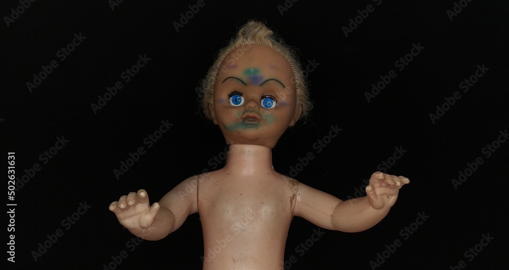 Scary, evil, spooky, demonic and possessed killer baby child girl doll head with creepy face and blue eyes on island of dead dolls during dark black night background with copy space. Closeup side view Scary, evil, spooky, demonic and possessed killer baby child girl doll head with creepy face and blue eyes on island of dead dolls during dark black night background with copy space. Closeup side view