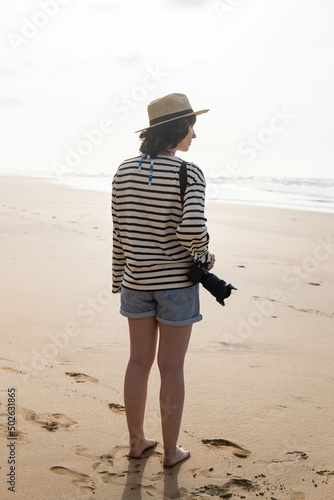 Obraz na płótnie Photo of a young and attractive woman with a photo camera wearing summer clothes at the beach. Photography, holidays, travel. w salonie