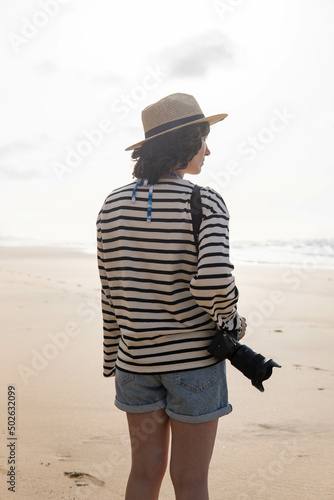 Obraz na płótnie Photo of a young and attractive woman with a photo camera wearing summer clothes at the beach. Photography, holidays, travel. w salonie