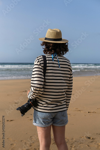 Obraz na płótnie Photo of a young and attractive woman with a photo camera wearing summer clothes at the beach. Photography, holidays, travel. w salonie