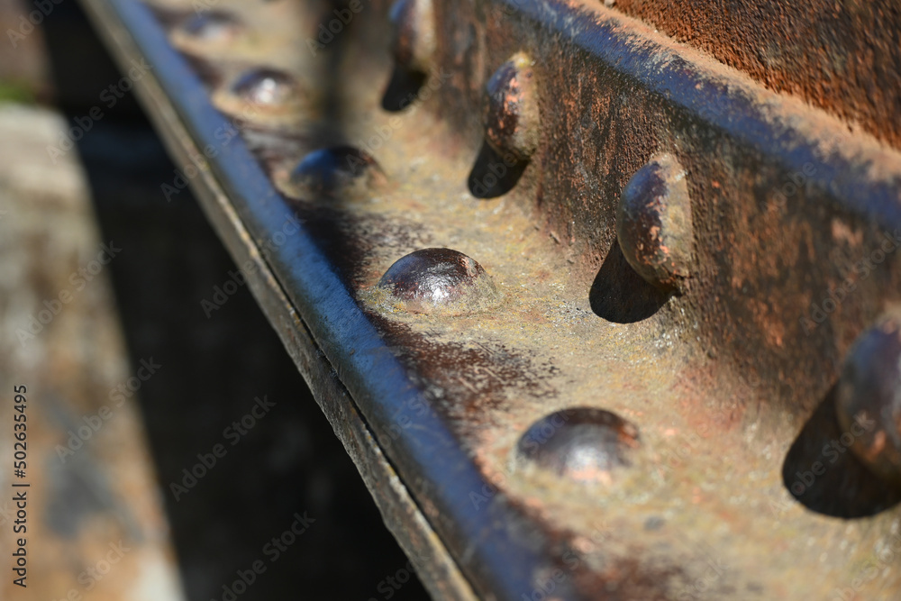 A fragment of an old rusty metal I-beam with rivets. Metal detail riveted with rivets close-up. A fragment of an old rusty metal I-beam with rivets. Metal detail riveted with rivets close-up.