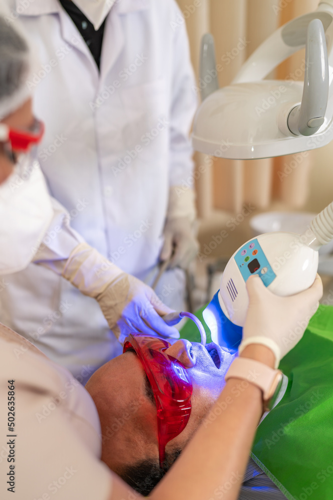 Obraz premium Latin man receiving a tooth whitening treatment in a clinic