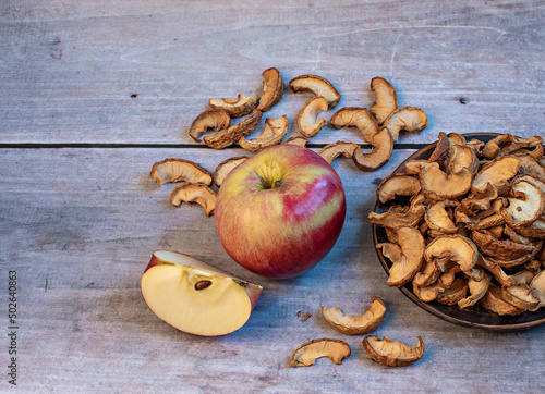 Dried apples in a bowl and ripe apple  on wooden background . Harvesting and drying apples. Dried apple slices on the table.Dried fruit chips. Healthy vegan food