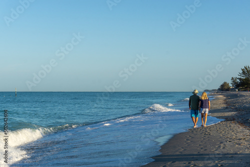 Sunrise stroll retired couple walk down beach in Florida