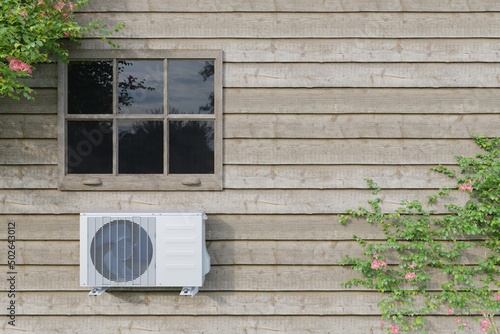 outdoor air conditioner unit on a wooden house with a window. 3d photo