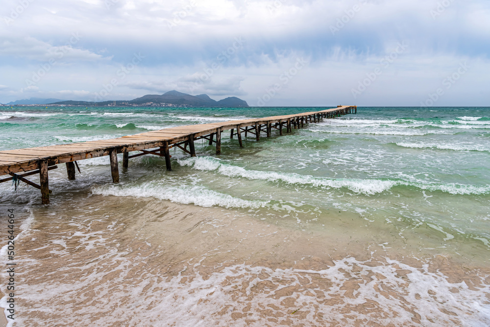 Majorca. Platja de Muro beach on a cloudy day. Wooden platform in the sea