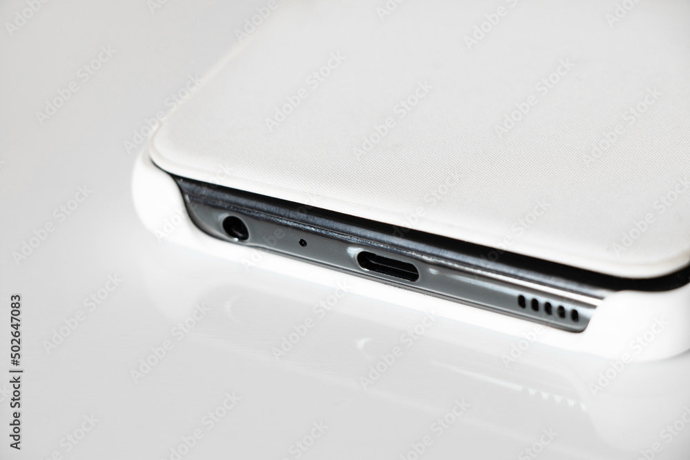 White phone lie on a white background close-up, a smartphone in a white case side view close up White phone lie on a white background close-up, a smartphone in a white case side view close up
