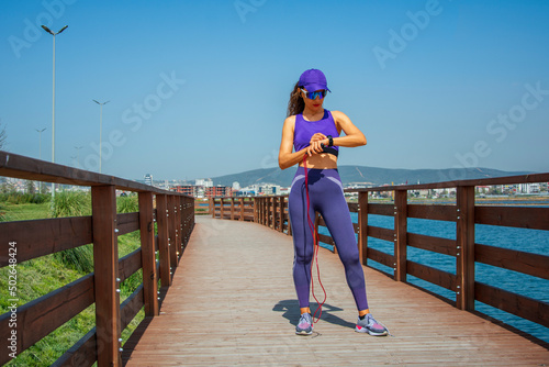 Beautiful woman adjusting her smart watch before jumping rope