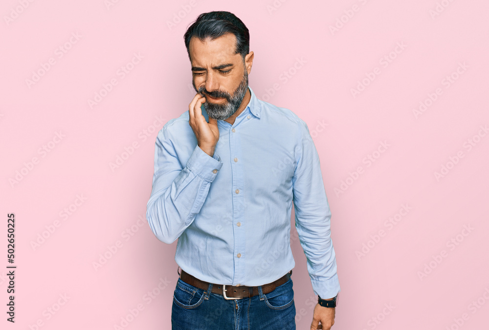 Fototapeta premium Middle aged man with beard wearing business shirt touching mouth with hand with painful expression because of toothache or dental illness on teeth. dentist