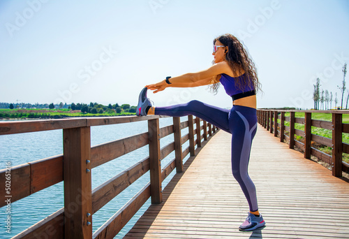 Woman stretching her body on the railings on the bridge