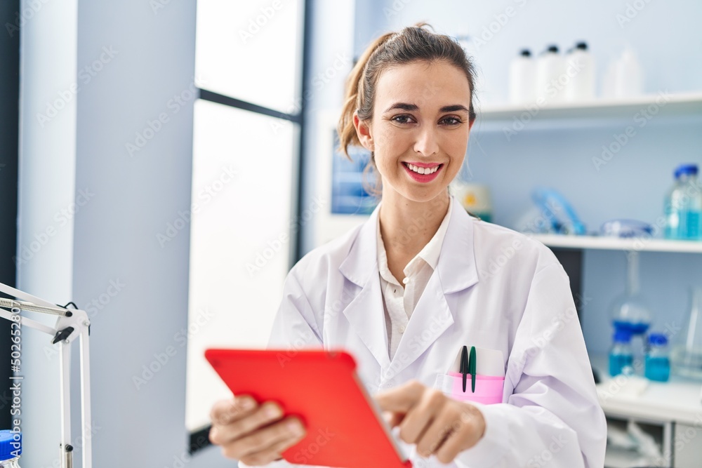 Young woman wearing scientist uniform using touchpad at laboratory Young woman wearing scientist uniform using touchpad at laboratory
