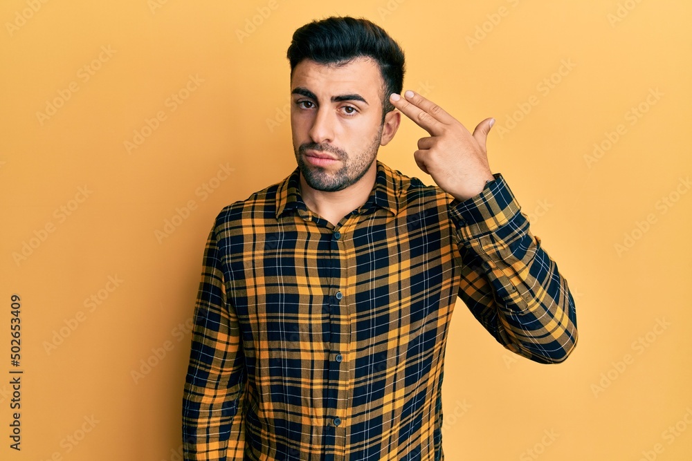 Young hispanic man wearing casual clothes shooting and killing oneself pointing hand and fingers to head like gun, suicide gesture. Young hispanic man wearing casual clothes shooting and killing oneself pointing hand and fingers to head like gun, suicide gesture.