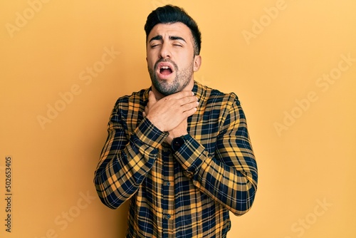 Young hispanic man wearing casual clothes shouting suffocate because painful strangle. health problem. asphyxiate and suicide concept.